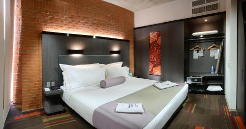a large white bed in a room with a brick wall at Hotel Guadalajara Country Club by HNF in Guadalajara
