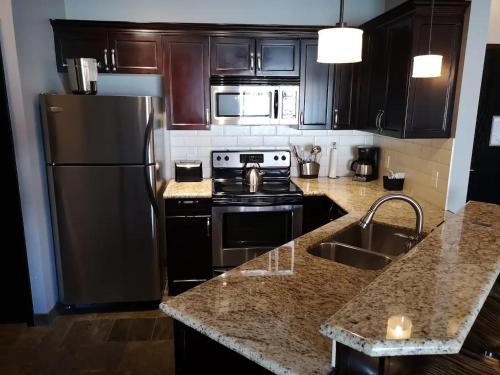 a kitchen with a black refrigerator and a sink at Sweet Condo Canmore GR：） in Canmore