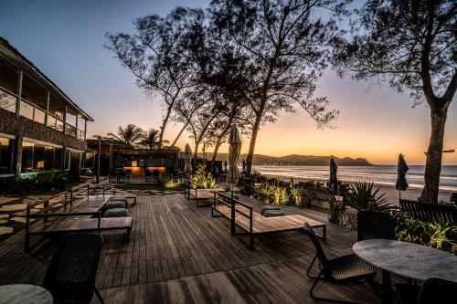 a patio with tables and chairs and the ocean at Pousada dos Gravatás in Búzios