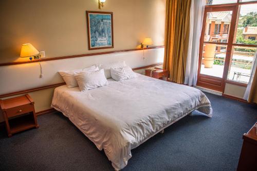 a bedroom with a large white bed with a window at Hotel Viña del Sur in Tarija