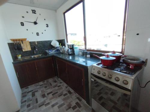 a kitchen with a stove and a clock on the wall at China Poblana's house in Puerto Baquerizo Moreno