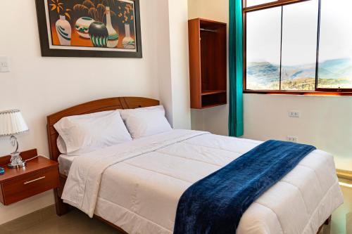 a bedroom with a bed with a blue blanket on it at HOSTAL EL MIRADOR CHACHAPOYAS in Chachapoyas
