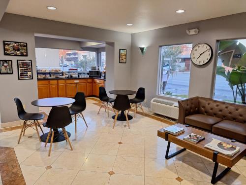 a living room with a couch and tables and a clock at Portofino Inn Burbank in Burbank