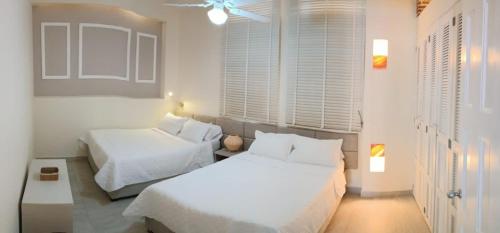 a white bedroom with two beds and windows at Hermoso Apto en el corazón de la ciudad amurallada in Cartagena de Indias
