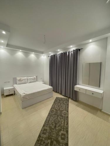 a white bedroom with a bed and a mirror at Apartments in Florenza Khamsin in Hurghada