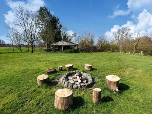 a fire pit in the middle of a field with logs at De Marckhoeve in Merksplas