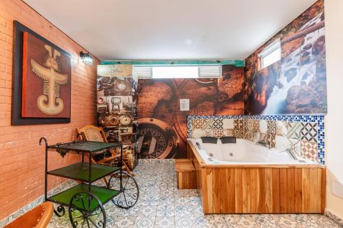 ボゴタにあるHotel Casa Antiguaの壁に絵画が飾られたバスルーム(バスタブ付)