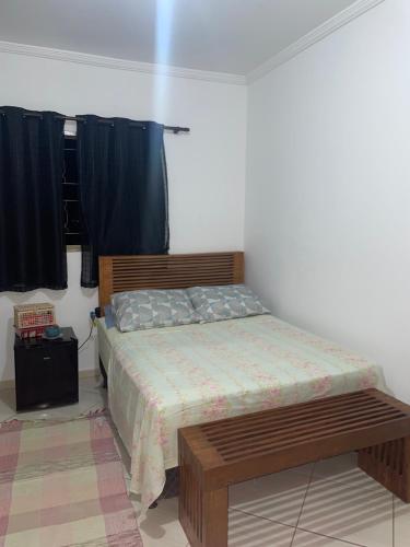 a bedroom with a bed and a bench in it at 1 quarto 1 cama queen size banheiro privativo- ap compartilhado in Alfenas