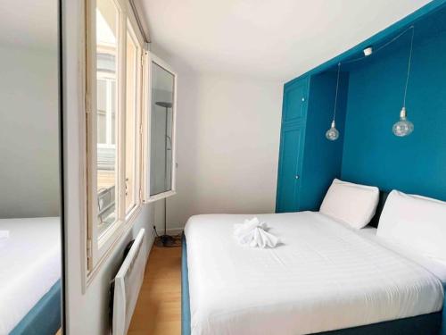 Cette chambre comprend 2 lits et un mur bleu. dans l'établissement Paris Cozy Flat, Sentier, 2 Guests, à Paris