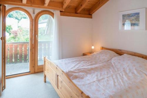 a bedroom with a bed and a large window at Casa Marianne - b48614 in Flims