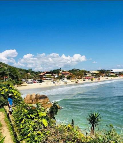uma praia com uma pessoa caminhando sobre a água em Aconchego Lagoinha Casa Frente em Florianópolis