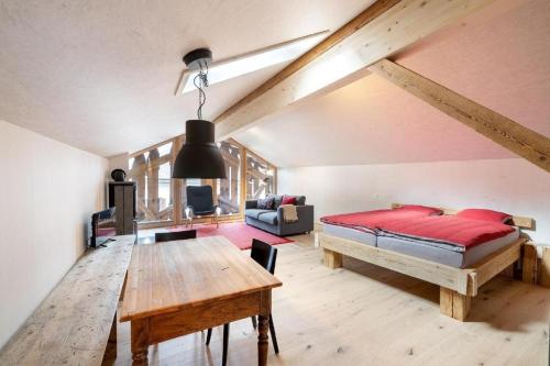 1 dormitorio con cama y mesa de madera en Bijou - BioBergün - b48615, en Bergün