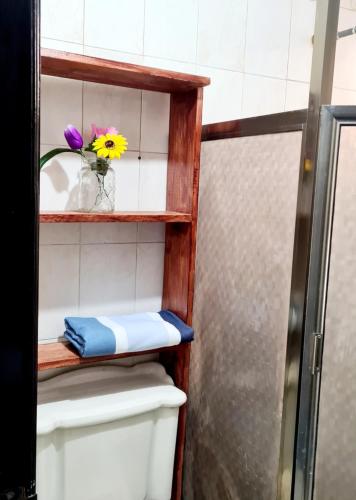 a bathroom with a toilet and a shelf with flowers on it at Cómoda habitación Mar in Veracruz