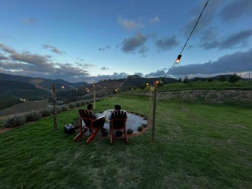 two people sitting in chairs in a field at dusk at Cabana em Domingos Martins in Domingos Martins