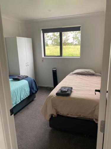 Un dormitorio con dos camas y una ventana. en Rural Guest Studio, en Kihikihi