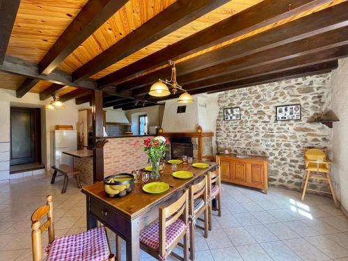 une cuisine avec une table et des chaises ainsi qu'un mur en pierre dans l'établissement Maison familiale 4 chambres avec jardin, cheminée, poêle à bois, parking et Wi-Fi - FR-1-582-230, à Saint-Vert