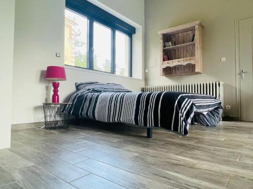 - une chambre avec un lit et une lampe sur du parquet dans l'établissement Gîte spacieux et lumineux dans belle dépendance avec terrasse privative, parc et chiens acceptés - FR-1-410-412, à La Flèche