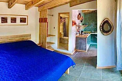 um quarto com uma cama azul e uma cozinha em Cabaña Roble em San Cristóbal de Las Casas