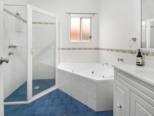 a white bathroom with a tub and a shower at Mar-Lin cute beach house in Callala Beach