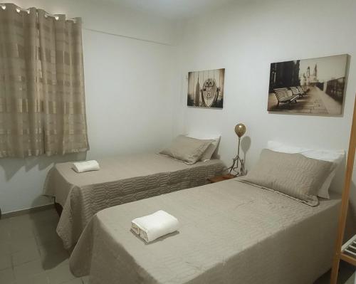 two beds in a white room with two towels at Apartamento Completo Praia de Camboinha in Cabedelo