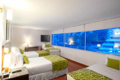 a hotel room with two beds and a window at Hotel Oceanía Bogotá Museo in Bogotá