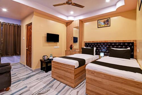 a hotel room with two beds and a tv at Super Collection O Hotel Mahal in Kolkata