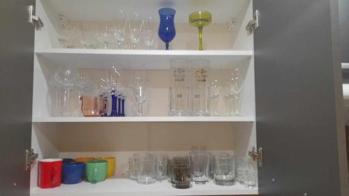a shelf filled with glasses and other glass items at Mieszkanie osiedle Północ Zameldowanie 24h in Koszalin
