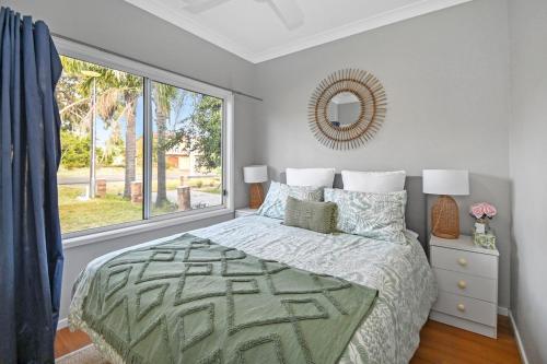 a bedroom with a bed and a large window at Mar-Lin cute beach house in Callala Beach