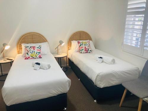 duas camas num quarto com duas cadeiras e candeeiros em The Platypus Accommodation & Cafe em Cudal