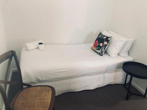 a white bed with a pillow and two chairs at The Platypus Accommodation & Cafe in Cudal