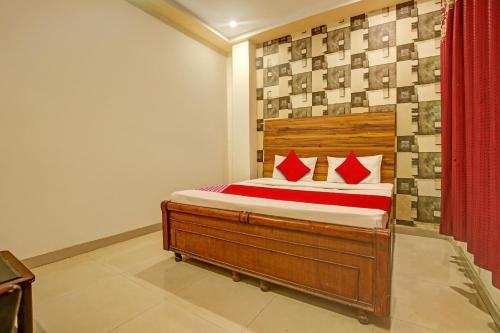Super OYO Hotel NR Residency في Banūr: غرفة نوم بسرير خشبي مع وسائد حمراء