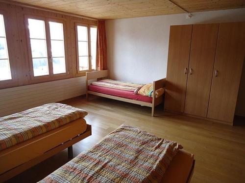 a bedroom with two beds and a cabinet and windows at Steffelhüs 8-Bettwohnung - b48637 in Hasliberg