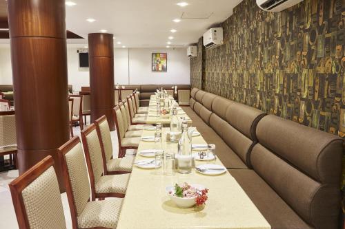 a long dining room with long tables and chairs at Hotel Reemz in Chiplun