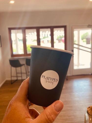 a person holding a coffee cup in their hand at The Platypus Accommodation & Cafe in Cudal