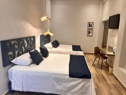 a bedroom with two beds and a desk at Centrico House in Taxco de Alarcón