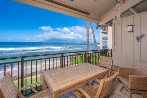 a balcony with a wooden table and chairs and the beach at B5 Pikake in Honokowai