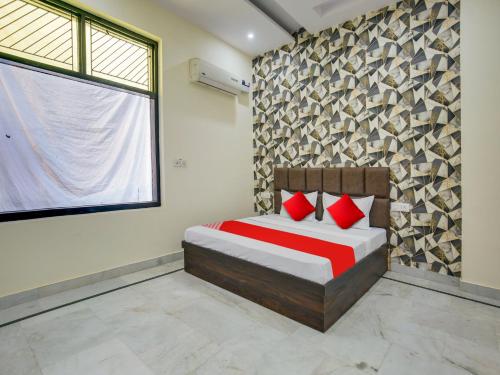 Schlafzimmer mit einem Bett mit roten Kissen und einem Fenster in der Unterkunft Super OYO Hotel Orchid Regency in Ludhiana