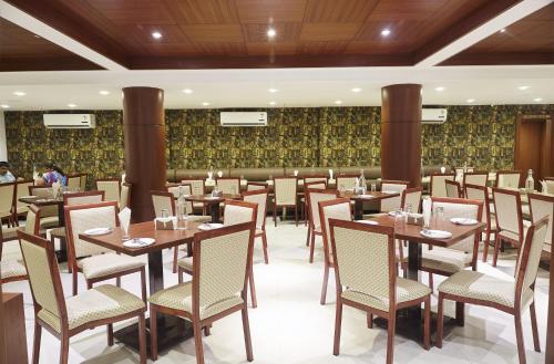 a dining room with wooden tables and chairs at Hotel Reemz in Chiplun
