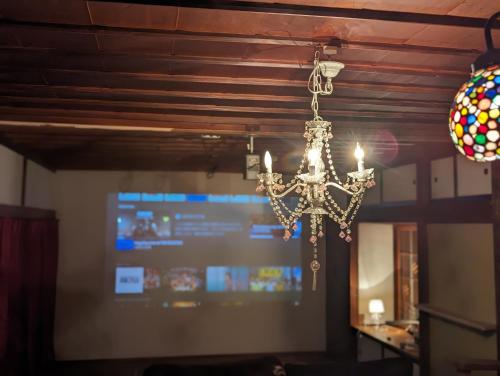 a chandelier hanging in front of a projection screen at CASA DE YOSHI MIHATACHOU 一棟貸 in Yamagata