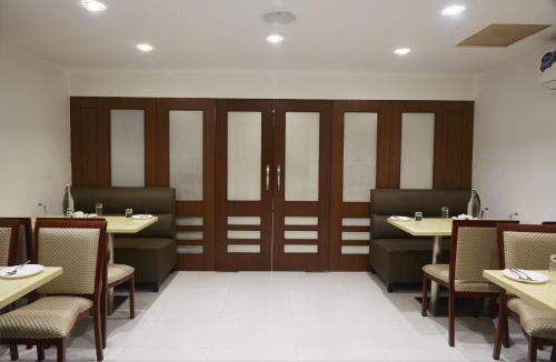 a dining room with tables and chairs and wooden doors at Hotel Reemz in Chiplun