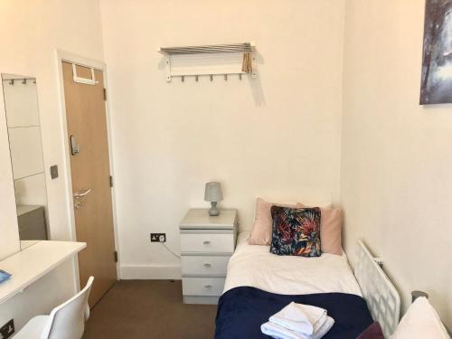 a small bedroom with a bed and a dresser at Metropolitan Coziness Private Bedrooms in Euston Station 161 in London