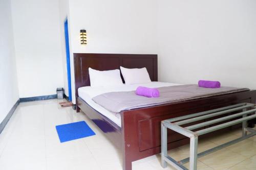 Una cama en una habitación con almohadas moradas. en Family Guest House Moni en Kelimutu