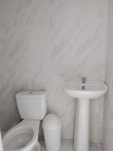 a white bathroom with a toilet and a sink at Nuestro Señor del Camino in Cajamarca