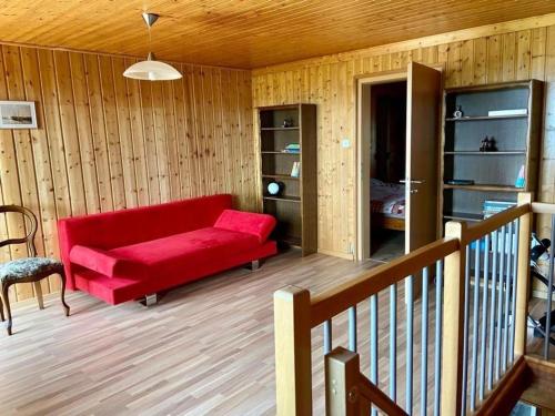 un sofá rojo en una sala de estar con paredes de madera en La Ferme - b48766, 