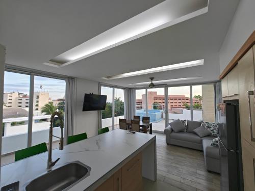 a kitchen and living room with a couch and a television at Hotel Plaza Huatulco Bungalows in Santa Maria Huatulco