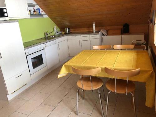 uma cozinha com uma mesa amarela e cadeiras em Ferienwohnung Fischbachboden - b48793 em Röthenbach