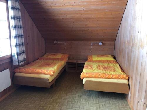 two beds in a room with wooden walls at Ferienwohnung Fischbachboden - b48793 in Röthenbach