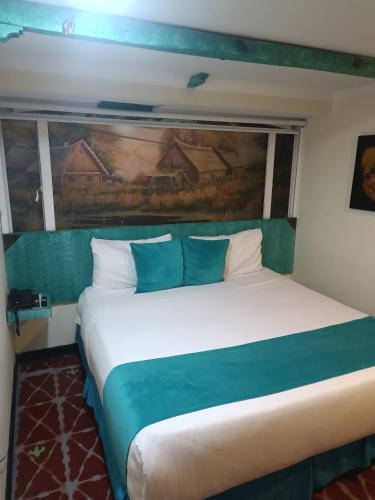 a bedroom with a large bed with a painting on the wall at Hotel Casa Antigua in Bogotá