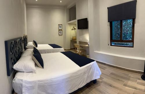 a bedroom with two beds and a desk and a window at Centrico House in Taxco de Alarcón