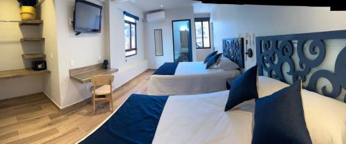 a bedroom with two beds and a television in it at Centrico House in Taxco de Alarcón